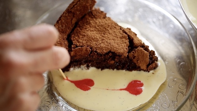 making raspberry hearts with a toothpick running through raspberry juice in a pool of creme anglaise