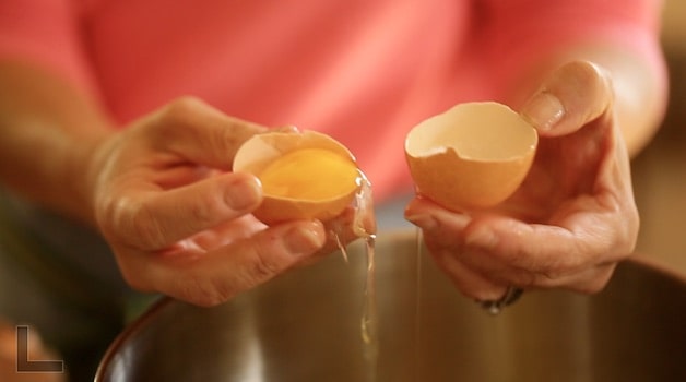 Holding egg cracked in two with yolk showing