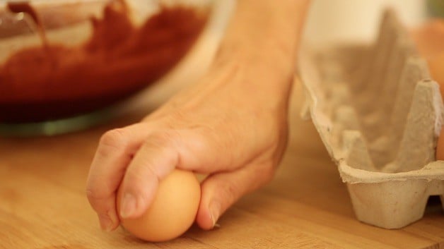 Cracking an egg on a wooden cutting board