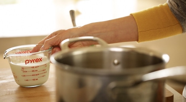 Reaching for milk in a pyrex measuring pitcher to place in pot