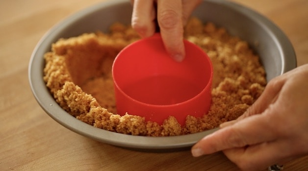 Creating a crumb crust with a measuring cup in a pie plate