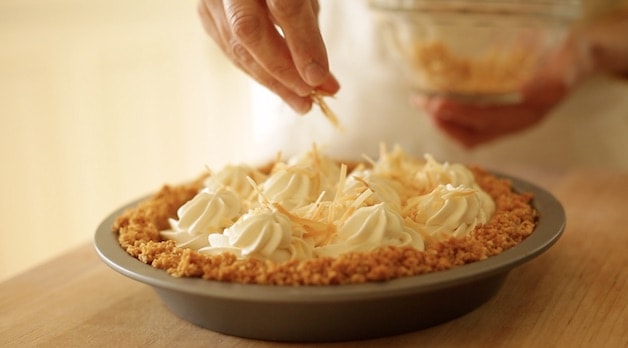 Coconut Cream Pie Recipe being topped with toasted coconut