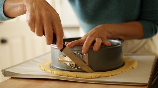 trimming sable Breton dough around a cheesecake ring