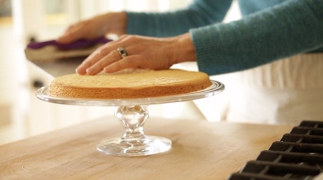 placing baked Sable Breton Crust on a clear glass cake stand