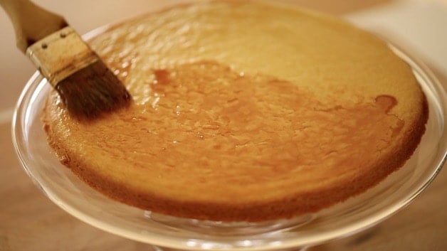 brushing strawberry jelly on a sable breton pastry base