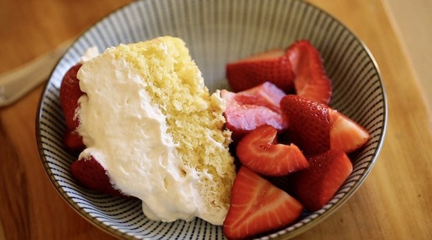 a slice of strawberry shortcake cheater charlotte on a blue plate with extra strawberries 