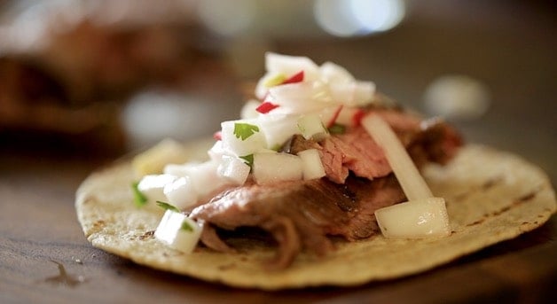 a fully assembled flank steak taco with Onion and Radish relish on a tortilla