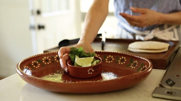 Placing a small bowl of limes and cilantro on a large Mexican Platter