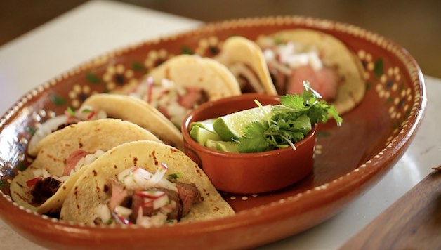 Assembling Carne Asada tacos on a Mexican platter