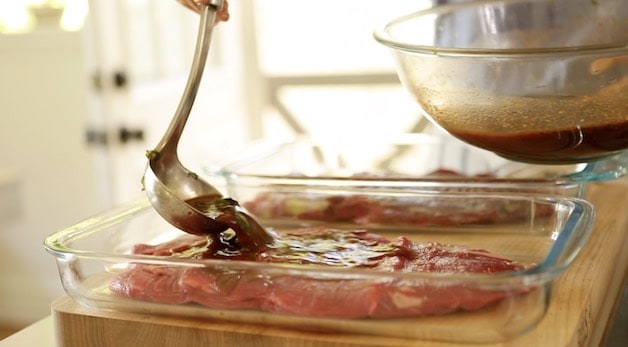 Pouring Marinade over a flank steak in a casserole dish