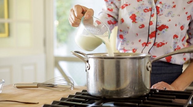 Adding milk to a large pot on a cooktop