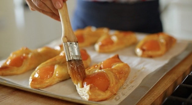 Brushing aprcot jam on apricot puff pastries