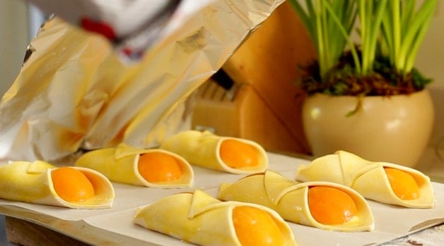 French pastries with apricots on a baking sheet lined with parchment paper