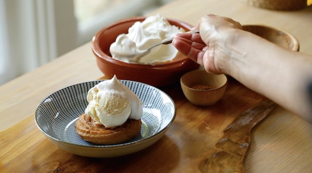 Churro Sundae on Blue plate being topped with homemade whipped cream 