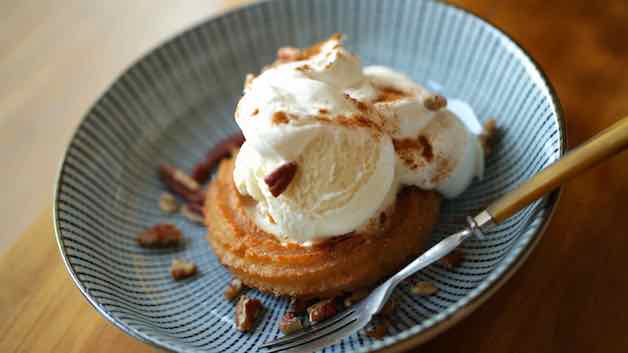 Churro Sundae on a blue plate with Whipped Cream, cinnamon and nuts