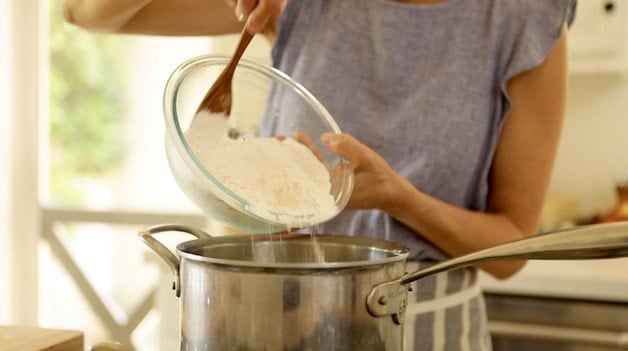 Adding dry ingredients to a pot for churro dough