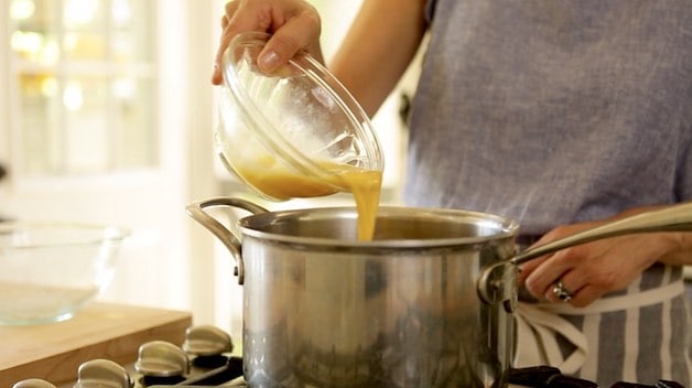 Adding beaten egg to a pot for a churro recipe