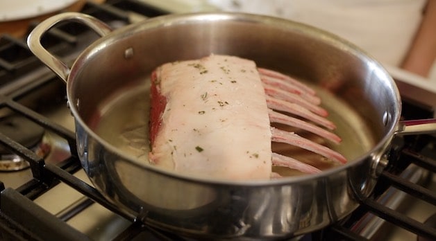 searing lamb rack in a pan