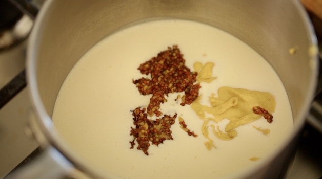 Heavy cream in a pot with 2 types of mustard ready to be stirred