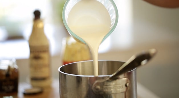 pouring heaving cream into a sauce pan