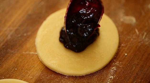 Placing blueberry jam on pie dough rounds