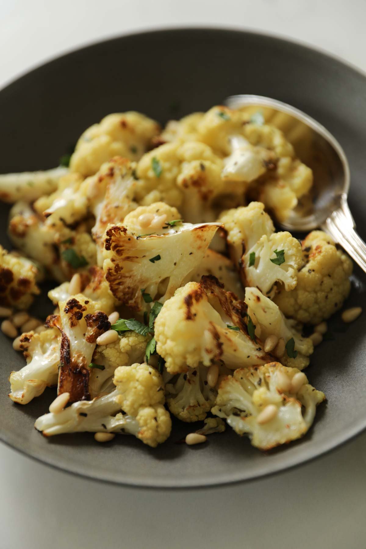Air fryer cauliflower in a gray bowl with silver spoon.