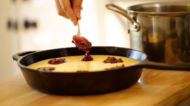 Blackberry puree being spooned into cornbread batter