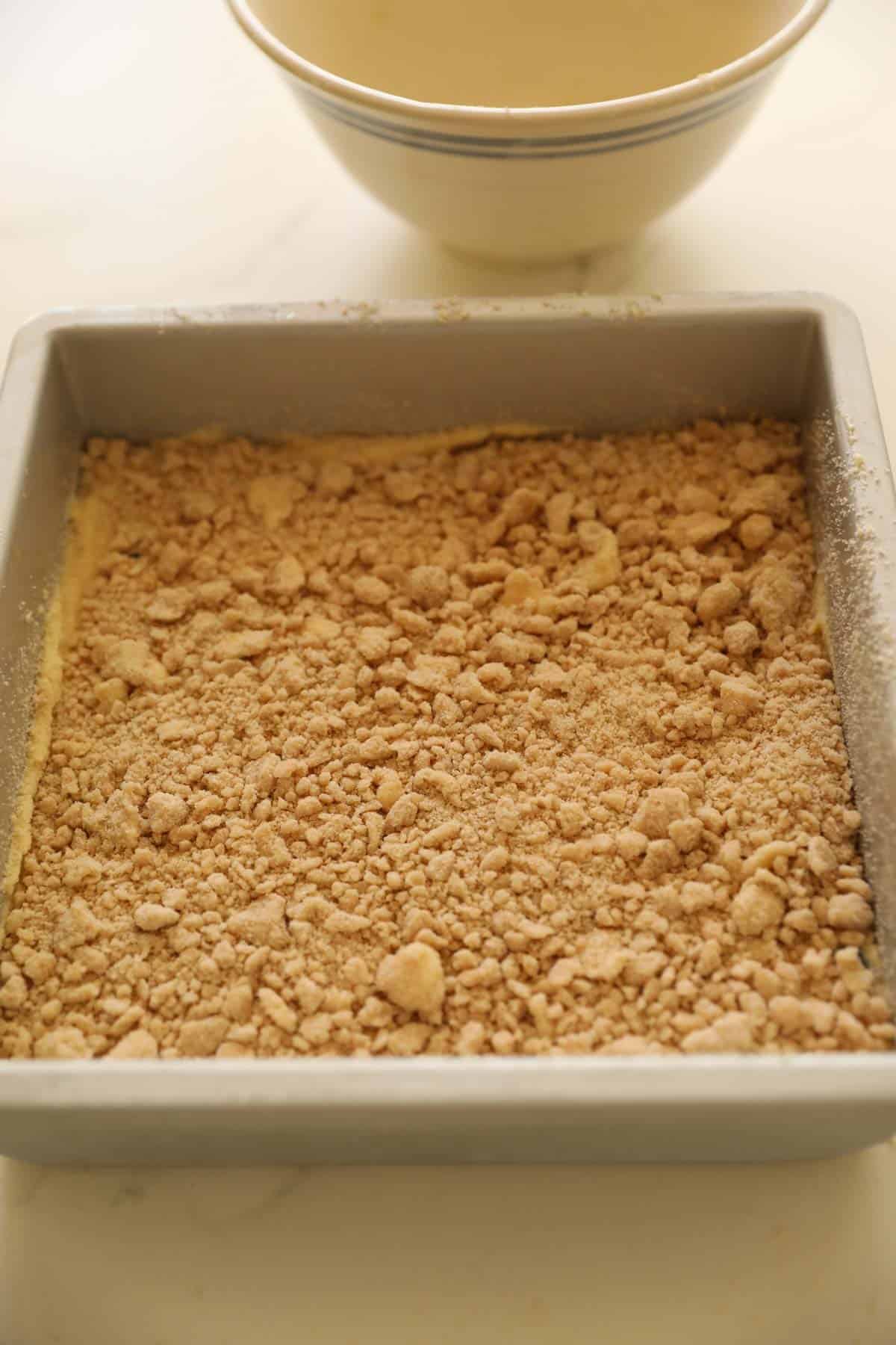 A square cake pan with crumb topping on top