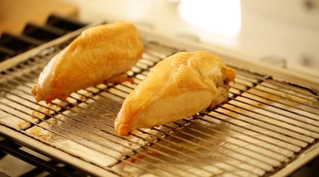 Bone-in, skin on Roasted Chicken breasts on a roasting rack in a sheet pan lined with foil