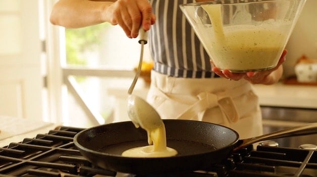 Ladling out crepe batter into a skillet