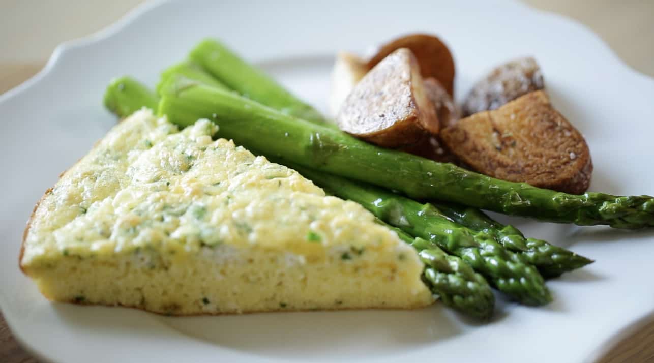 A slice of Egg Bake Casserole with roasted potatoes and asparagus