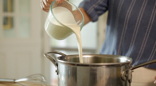 adding heavy cream to a large sauce pot