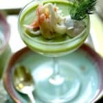 Vertical image of a savory panna cotta with sweet pea and king crab, in a 1930's style champagne coupe