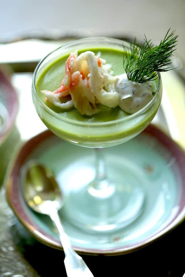 Vertical image of a savory panna cotta with sweet pea and king crab, in a 1930's style champagne coupe