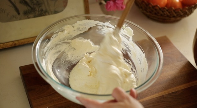 Mixing frosting in a clear bowl with a spatula