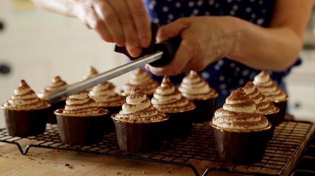 Grating chocolate on top of tiramisu cupcakes