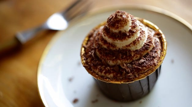 a tiramisu cupcake on a light blue plate with fork 