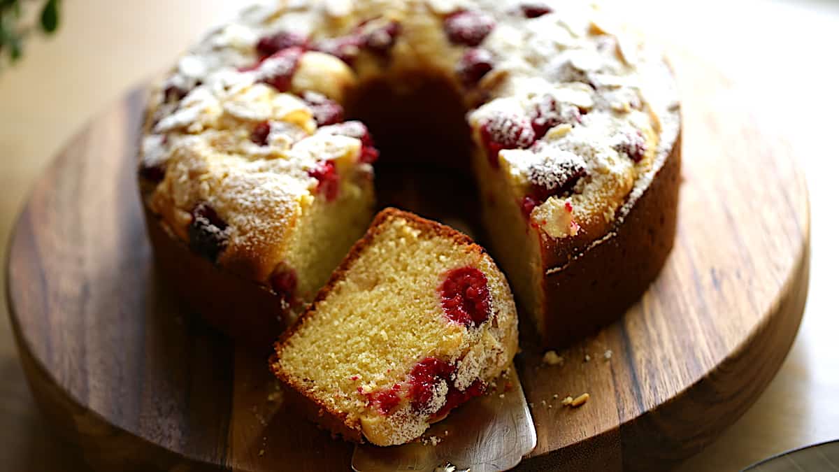 Raspberry Almond Cake on board with a slice showing the texture