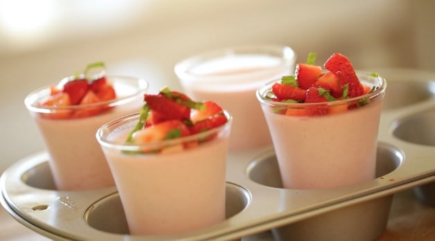 Cups of Strawberry Panna Cotta topped with strawberries on a tray