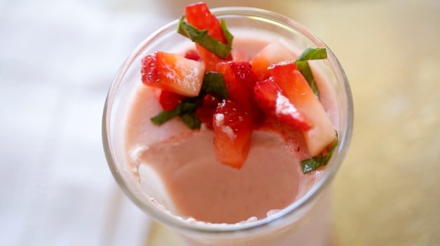 A cup of Strawberry Panna Cotta topped with strawberries with a bite taken out