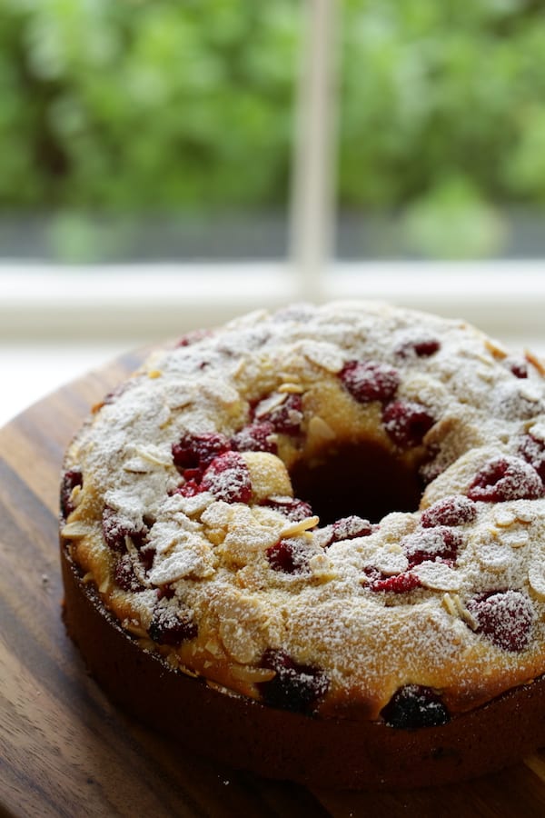 Raspberry Almond Cake dusted with powdered sugar on a cutting board