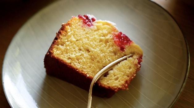 A fork taking a bite out of a slice of raspberry almond cake