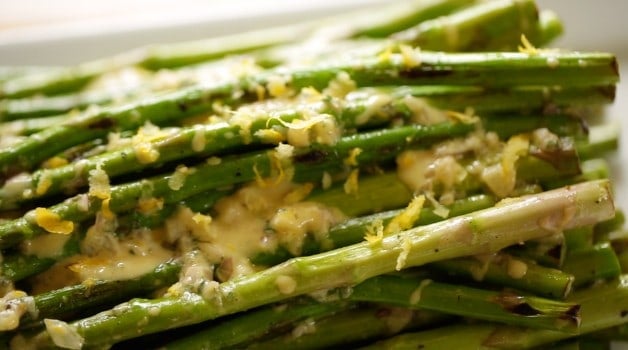 A close up of a Charred Asparagus Salad with dressing and lemon zest