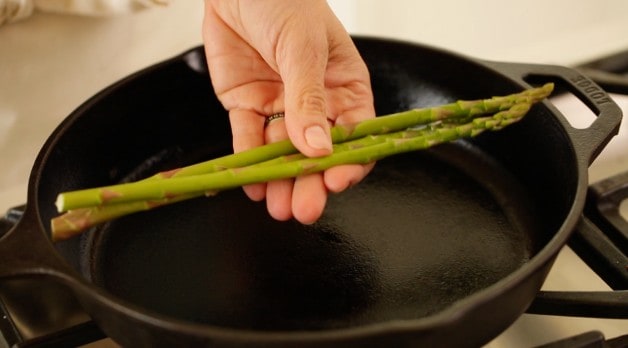 Holding Asparagus Spears over a cast-iron skillet