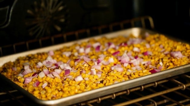 Corn and red onion on baking sheet in the oven