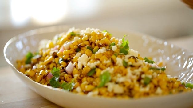 Queso Fresco Cheese crumbled on top of a corn salad in a white platter