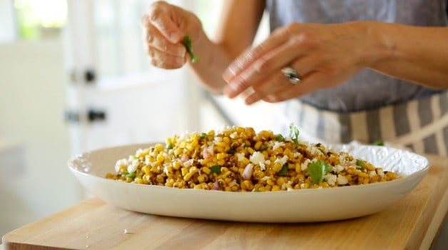 adding cilantro to a completed charred corn salad