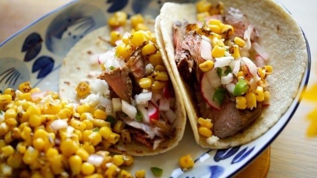 Charred Mexican Corn Salad Recipe over tacos on white a blue plate