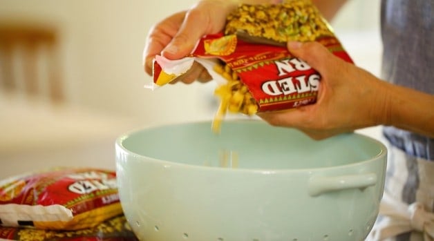 Frozen corn being placed into a blue collander