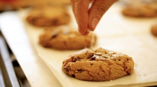 adding seas salt to the top of a browned butter chocolate chip cookie